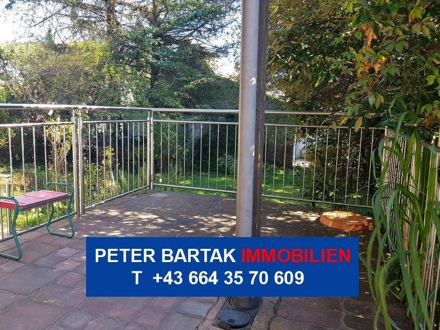 Gepflasterte Terrasse mit Metallgeländer und Blick ins Grüne.