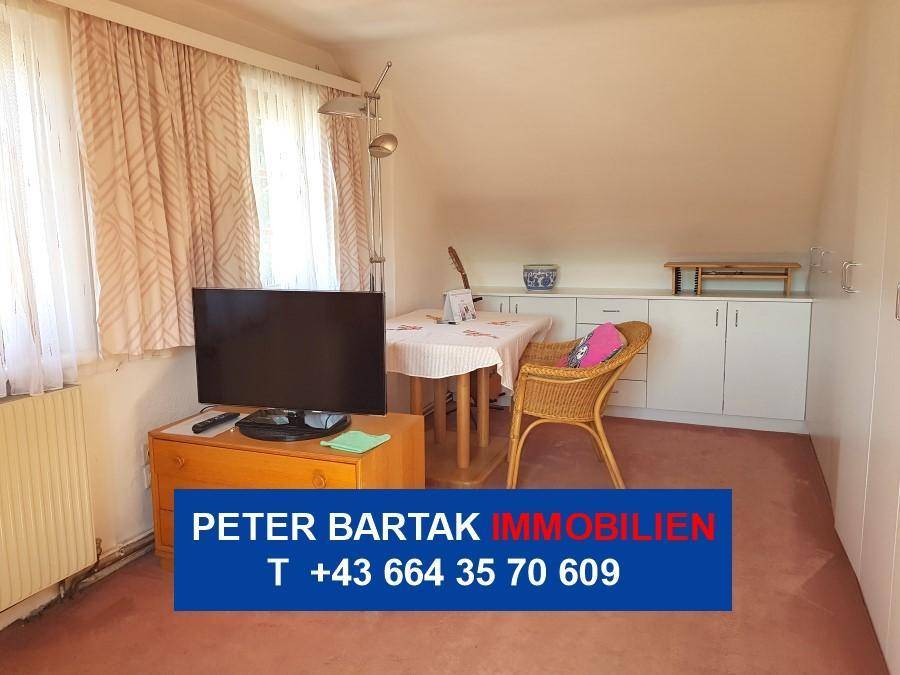 Vielseitiges Dachzimmer mit kleinem Esstisch, Fernseher und Einbauschränken.