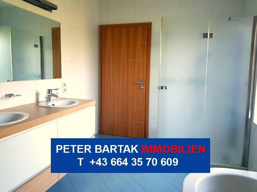 Modernes Badezimmer mit Doppelwaschbecken, großem Spiegel und einer Duschkabine aus Glas.