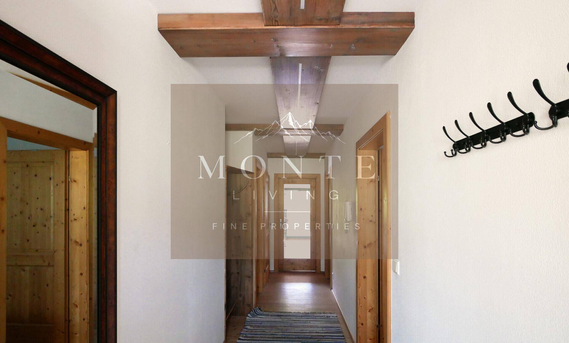 Heller Flur mit Holztüren, sichtbaren Deckenbalken und Garderobe.