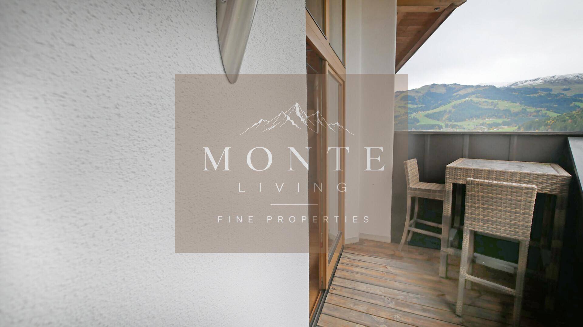 Kleiner Balkon mit Rattanmöbeln und Blick auf die umliegende Berglandschaft.