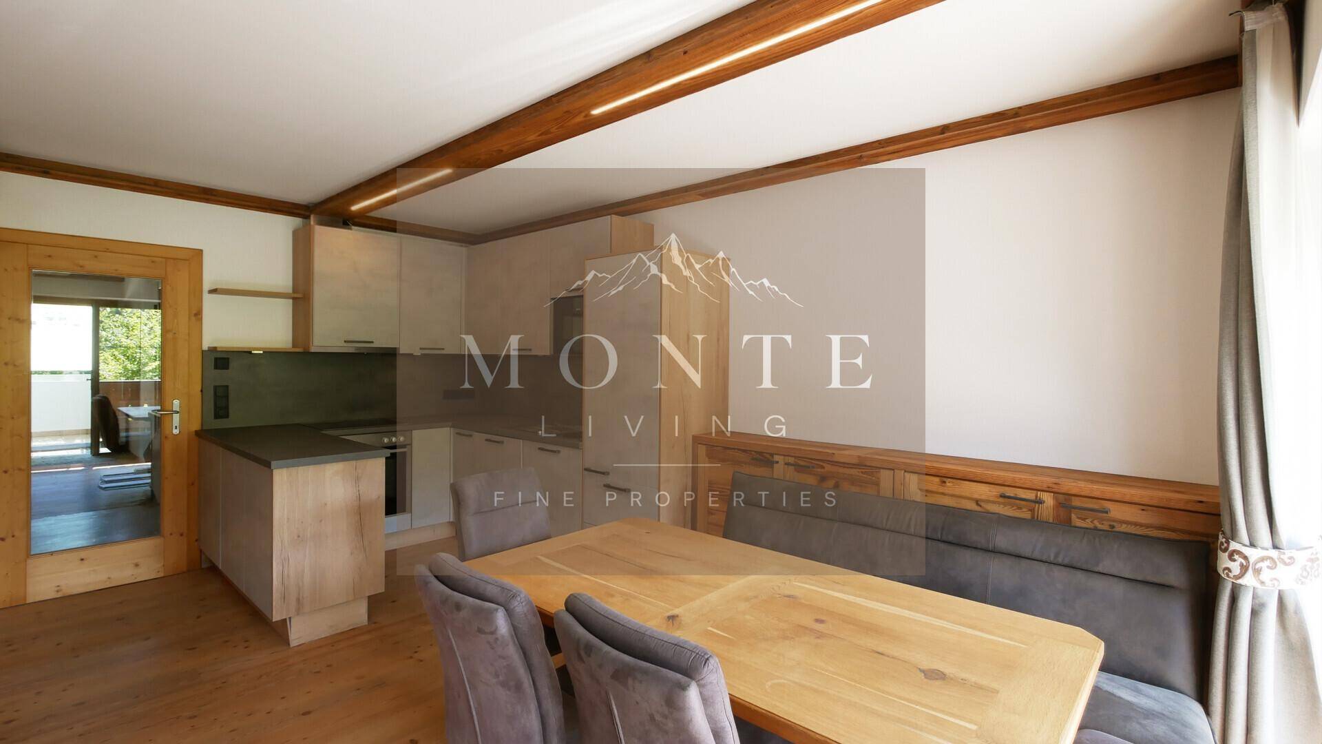 Offene Wohnküche mit Essbereich, modernen Schränken und Holzbalken an der Decke.