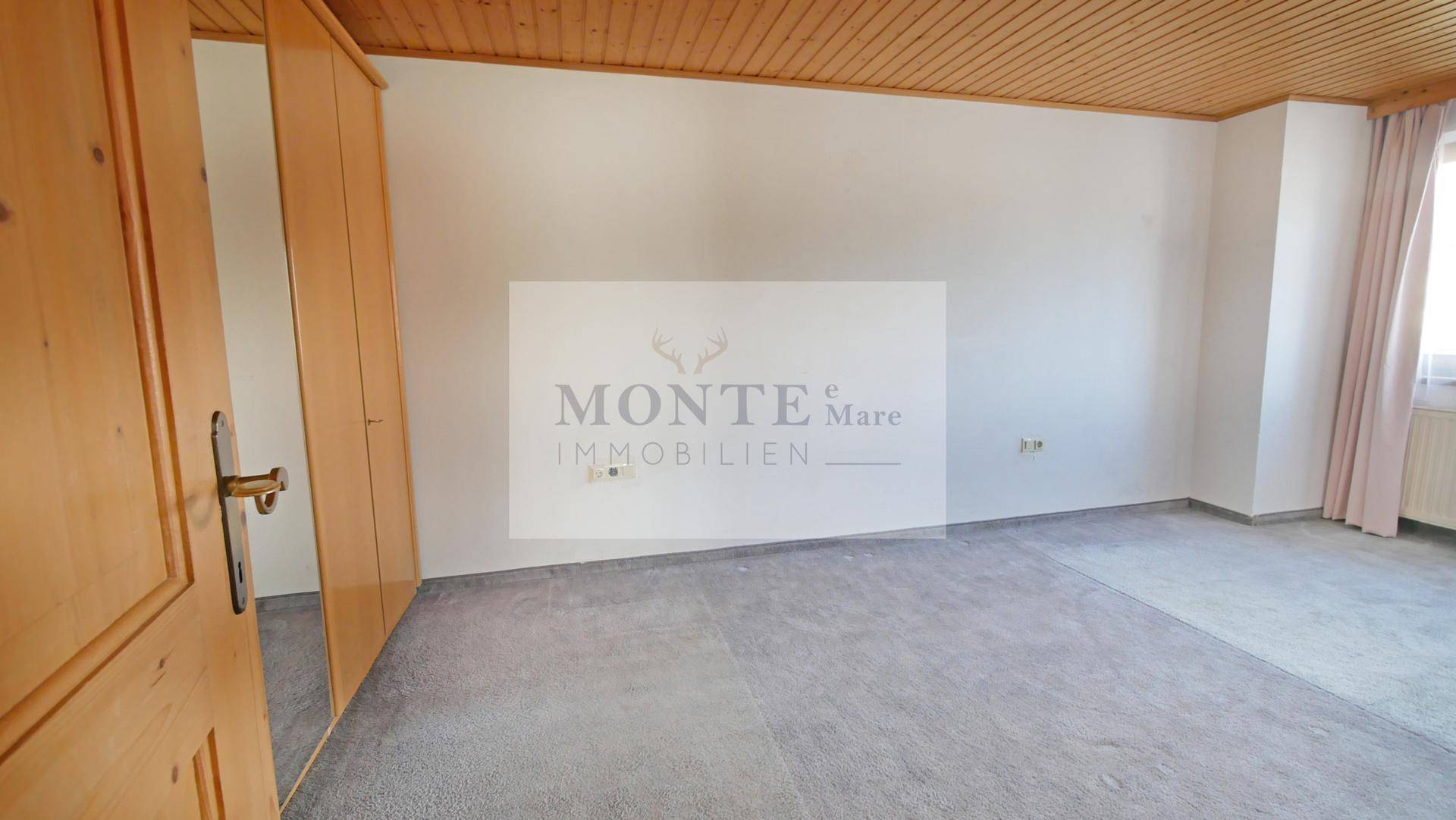 Helles Schlafzimmer mit Holztür, Einbauschrank und modernem Bodenbelag.