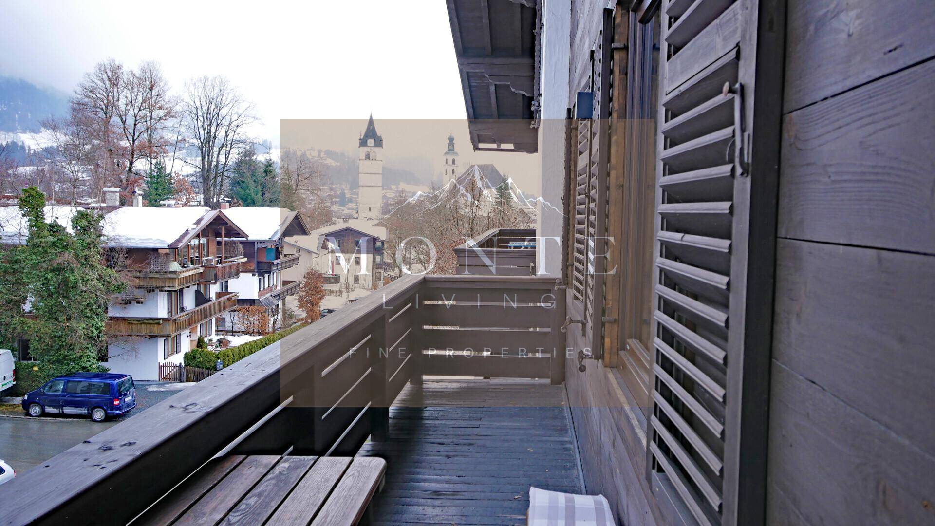 Gemütlicher Holzbalkon mit Blick auf die umliegende Berglandschaft und traditionelle Häuser.