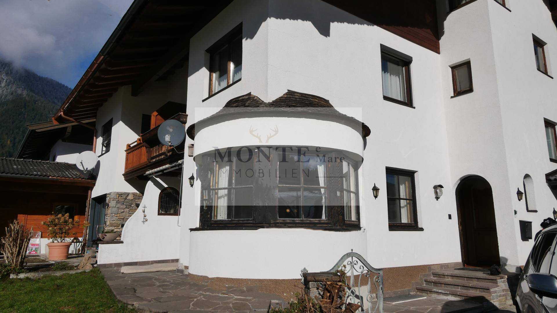 Traditionelles Haus im alpinen Stil mit weißer Fassade und Holzbalkonen.