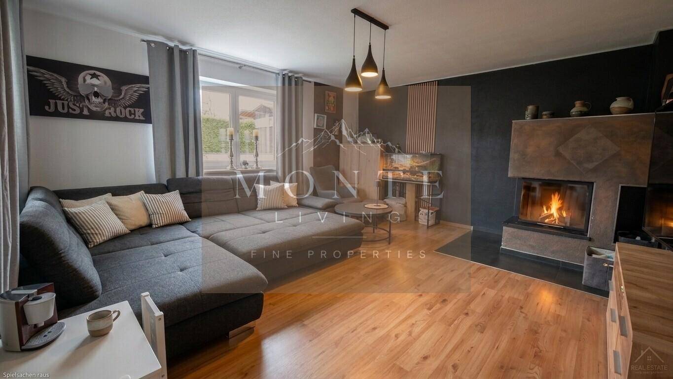 Gemütliches Wohnzimmer mit modernem Kamin, großem Sofa und Holzboden.