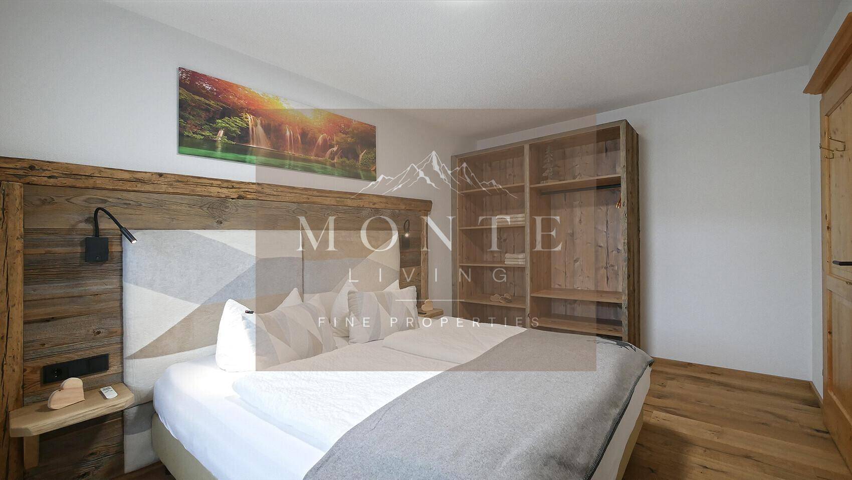 Schlafzimmer mit rustikalem Holzbett, offenem Kleiderschrank und Holzboden.