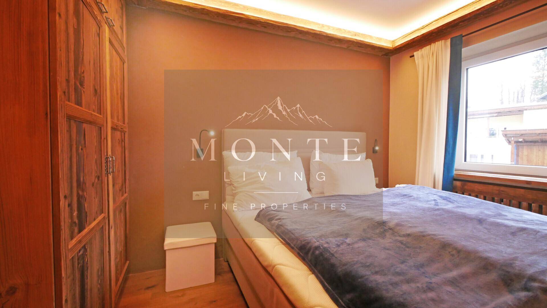 Schlafzimmer mit Doppelbett, Holzkleiderschrank, Parkettboden und indirekter Deckenbeleuchtung.