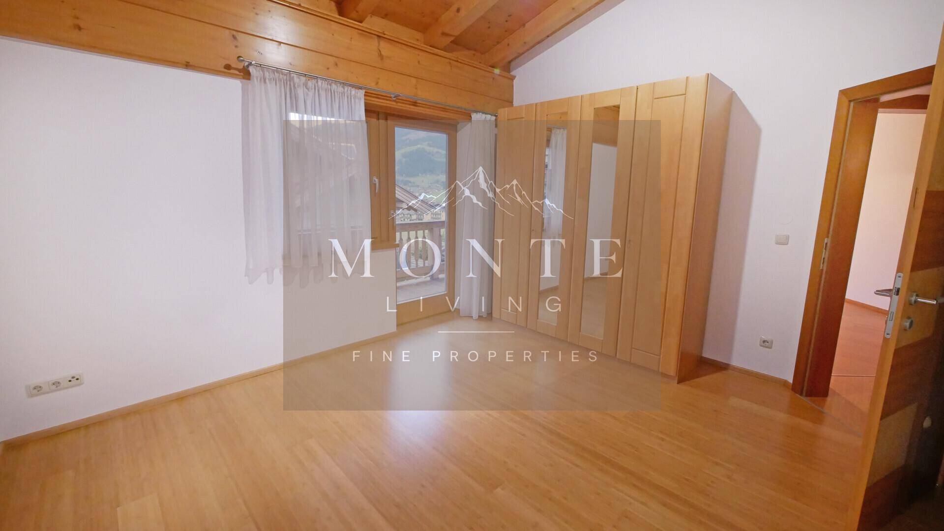 Gemütliches Schlafzimmer mit Holzboden, Einbauschrank und direktem Zugang zum Balkon.