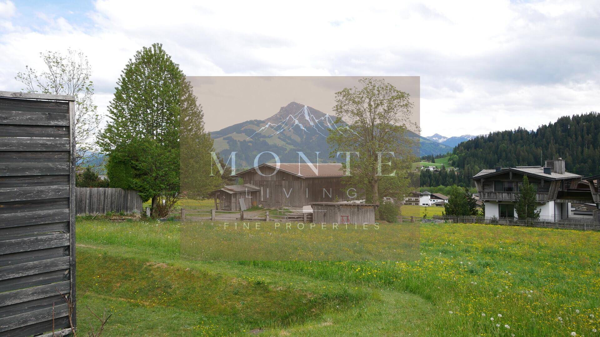 Weitläufige grüne Wiesen mit traditioneller Scheune und majestätischem Bergblick.