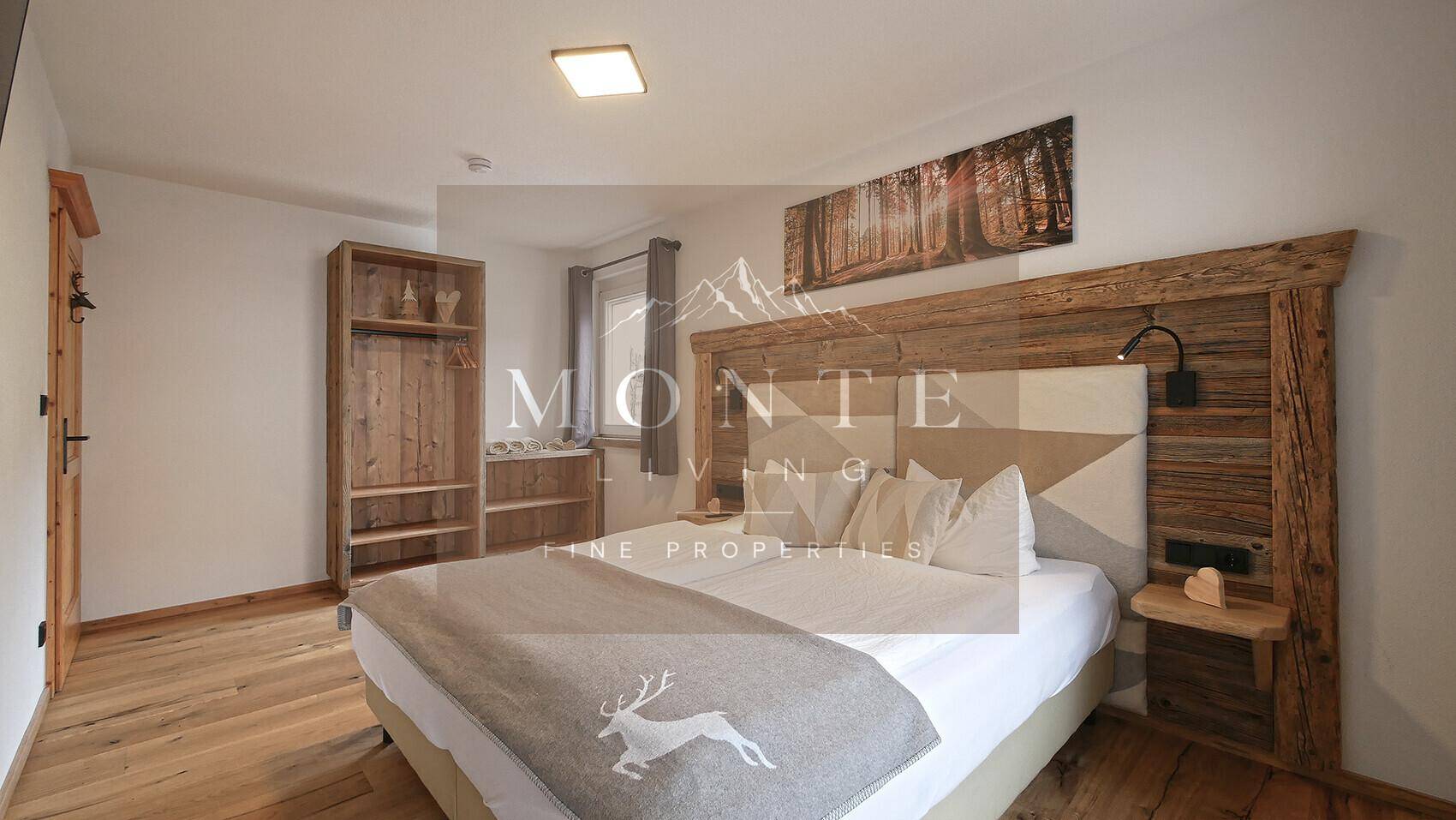 Helles Schlafzimmer mit rustikalem Holzbett, offenem Kleiderschrank und Fenster.