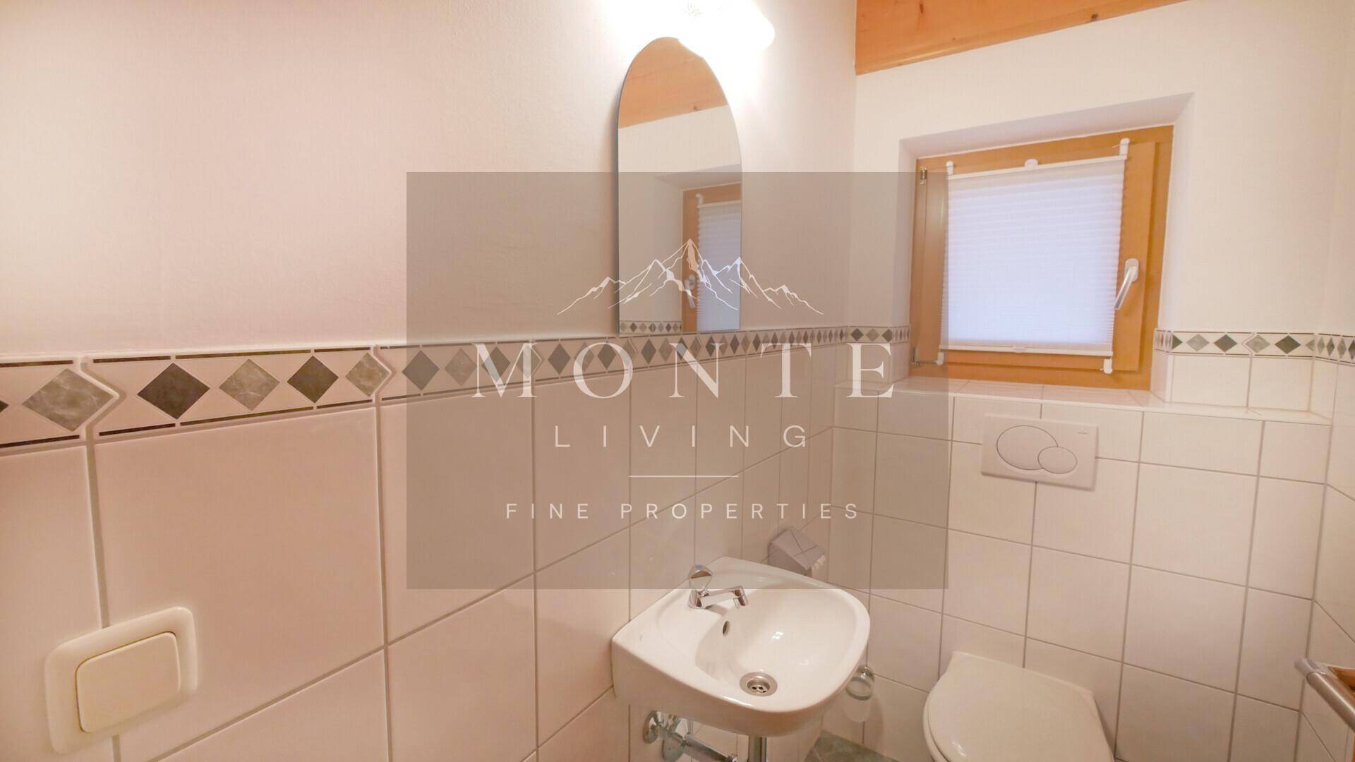 Kleines Gäste-WC mit Waschbecken, Toilette und Fenster für natürliche Belüftung.