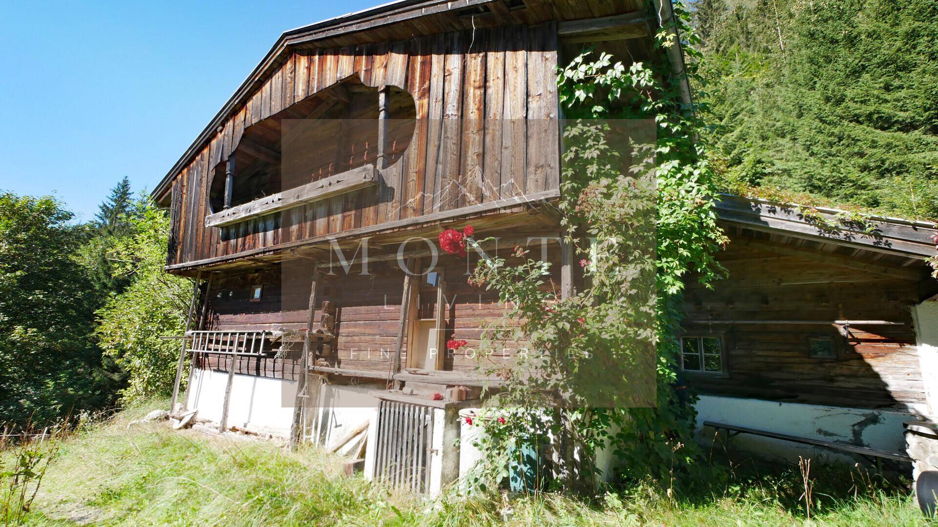 Rustikales Holzhaus im Chalet-Stil mit traditioneller Architektur und umgebender Natur an einem Hang.