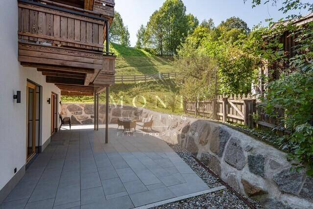 Geräumige Terrasse mit Steinmauern, Sitzgelegenheiten und Blick auf die grüne Umgebung.