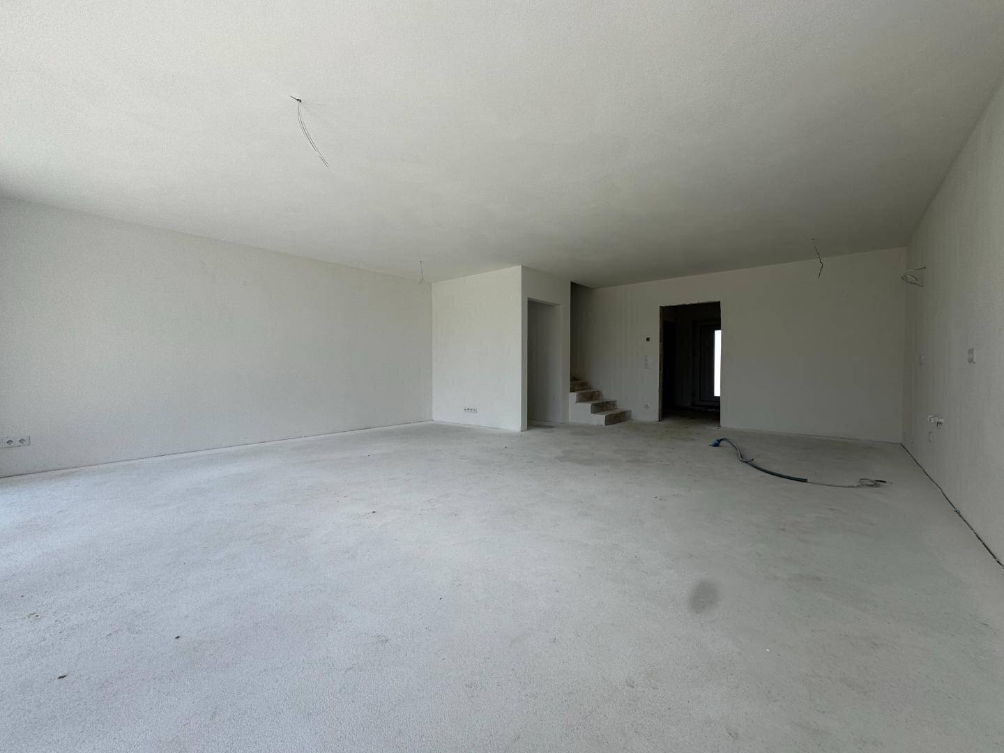 Heller, unmöblierter Wohnbereich im Rohbau mit viel Potenzial zur Gestaltung.