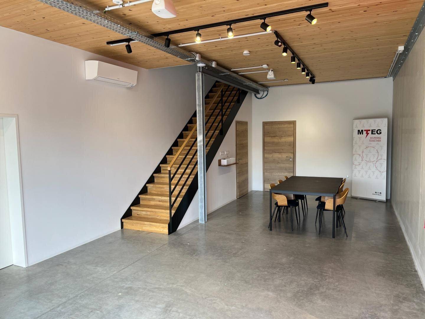 Moderner Empfangsbereich mit Holzbalkendecke, Treppe und Klimaanlage, einladend und funktional gestaltet.