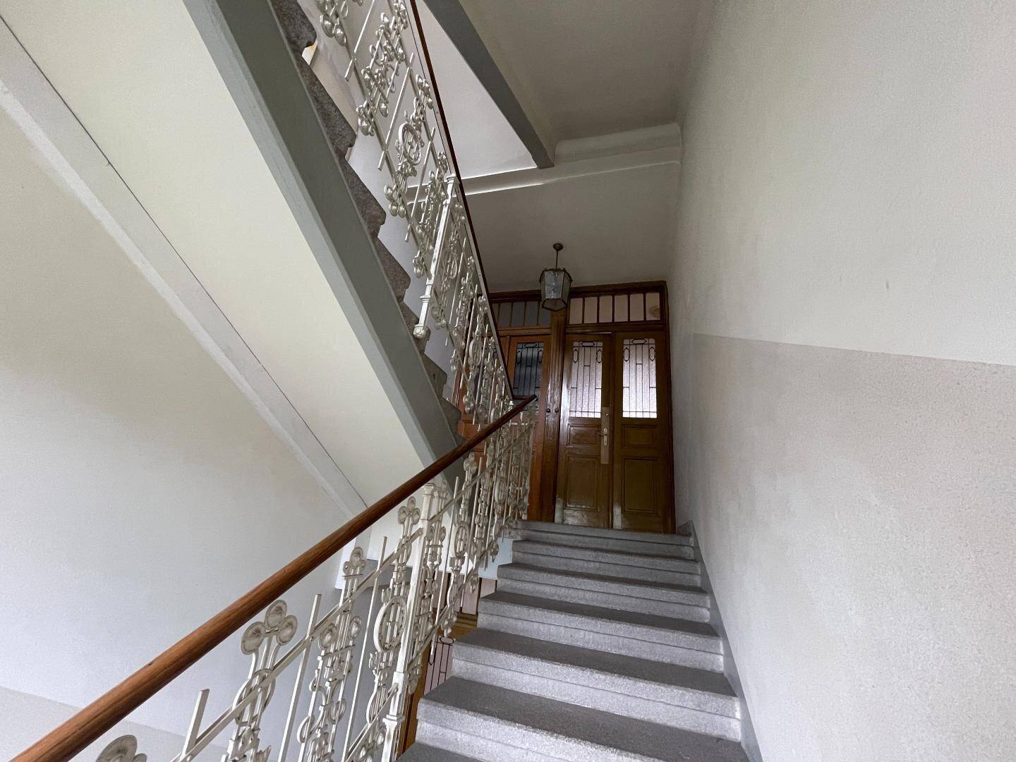 Historisches Treppenhaus mit kunstvollem Geländer und Holztüren im klassischen Altbaustil.
