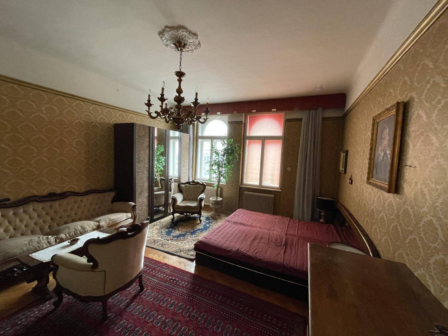 Geräumiges Schlafzimmer mit traditionellen Möbeln, gemusterter Tapete und einem großen Bett, das zum Entspannen einlädt.