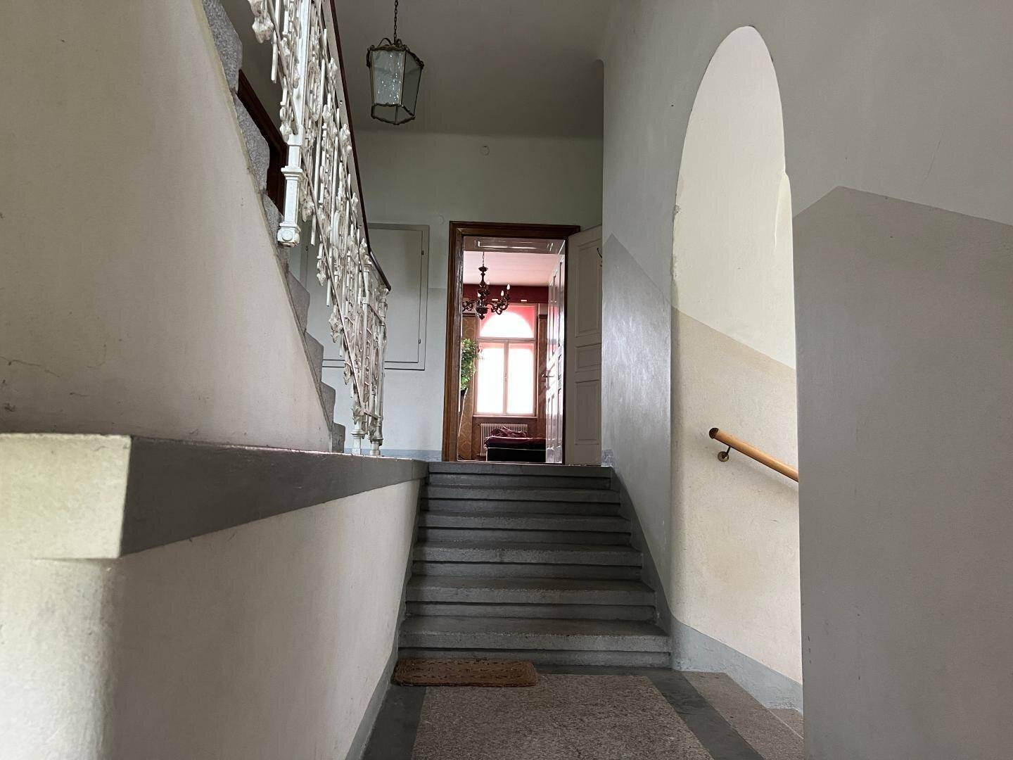 Treppenabsatz in einem historischen Gebäude mit Blick auf eine offene Tür zu einem Zimmer.