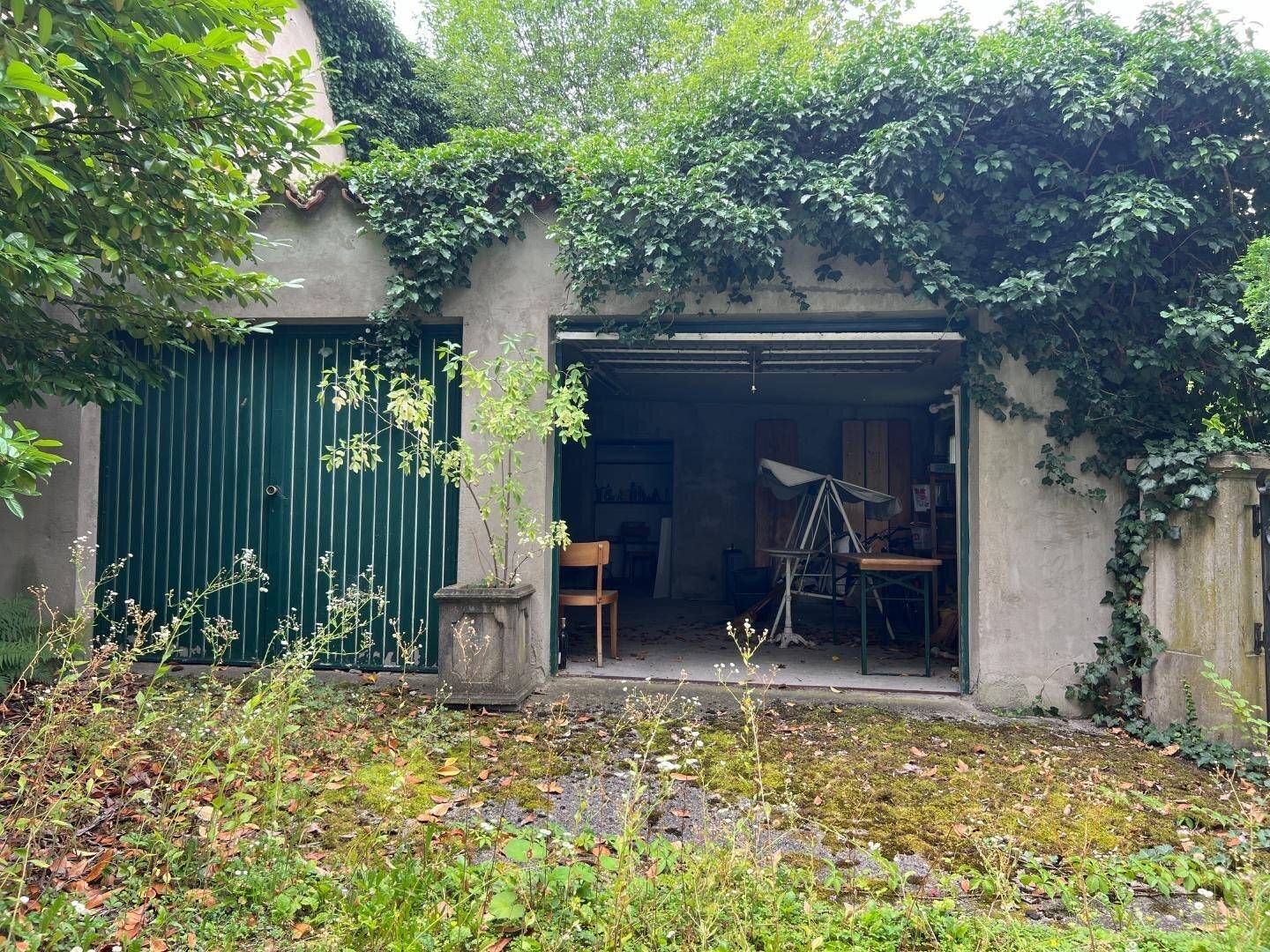Alte Garage mit zwei Toren, eines davon offen, um einen unaufgeräumten Innenraum zu zeigen.