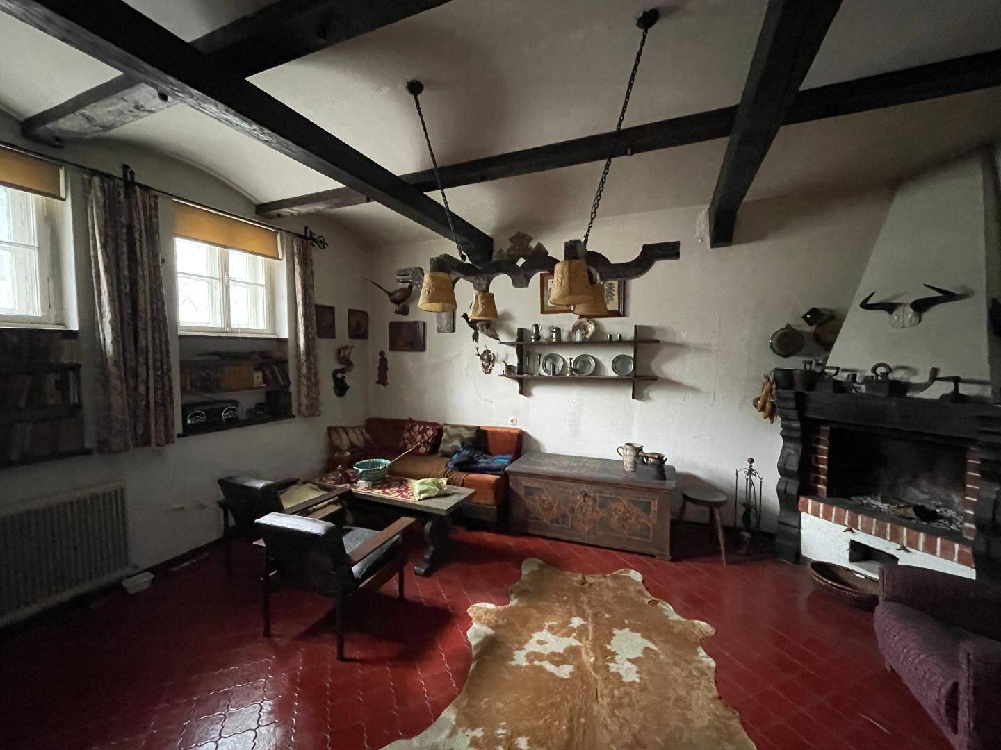 Rustikales Wohnzimmer mit Holzbalken, Kamin und traditioneller Einrichtung im alpinen Stil.