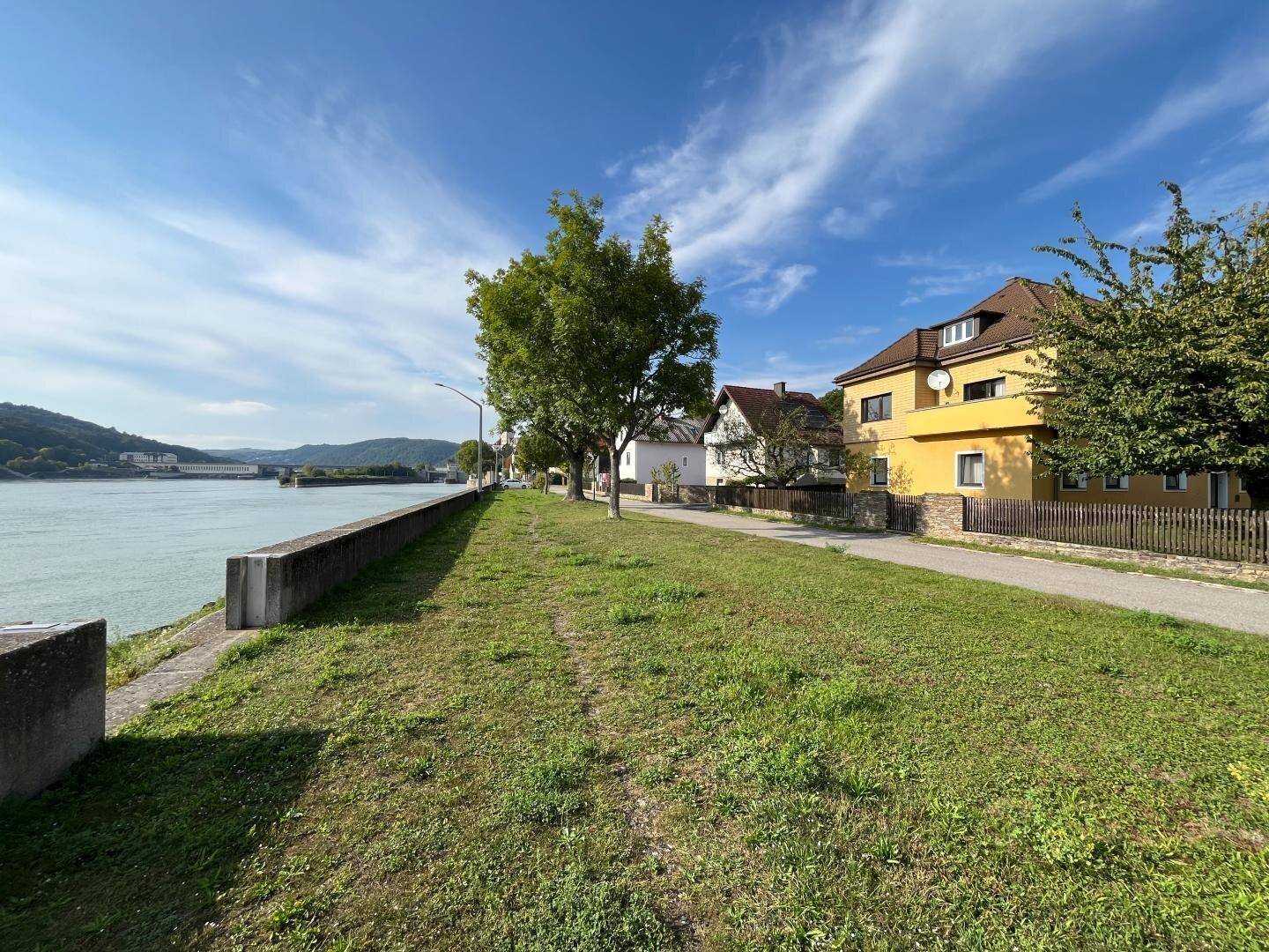 Panoramablick auf den Fluss mit dem gelben Haus und weiteren Gebäuden am Ufer.