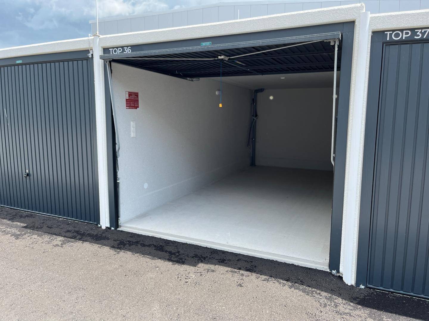 Helle und geräumige Garagenbox mit offenem Rolltor und sauberem Betonboden.
