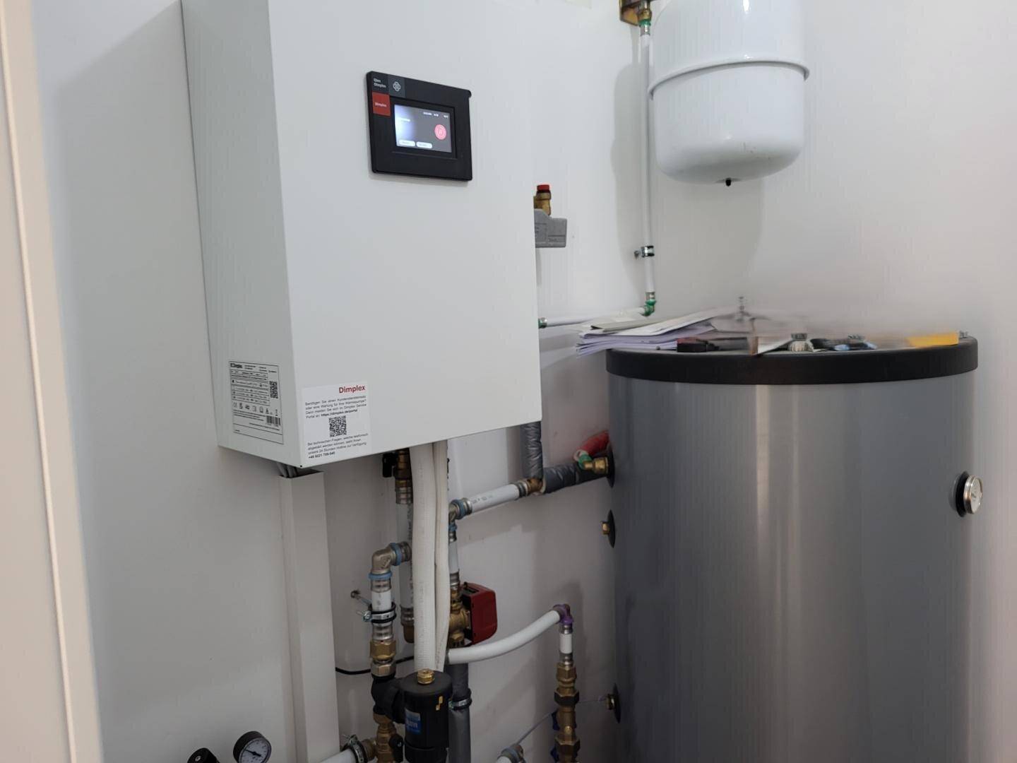 Technikraum mit moderner Wärmepumpe und Warmwasserspeicher für effiziente Heizung.
