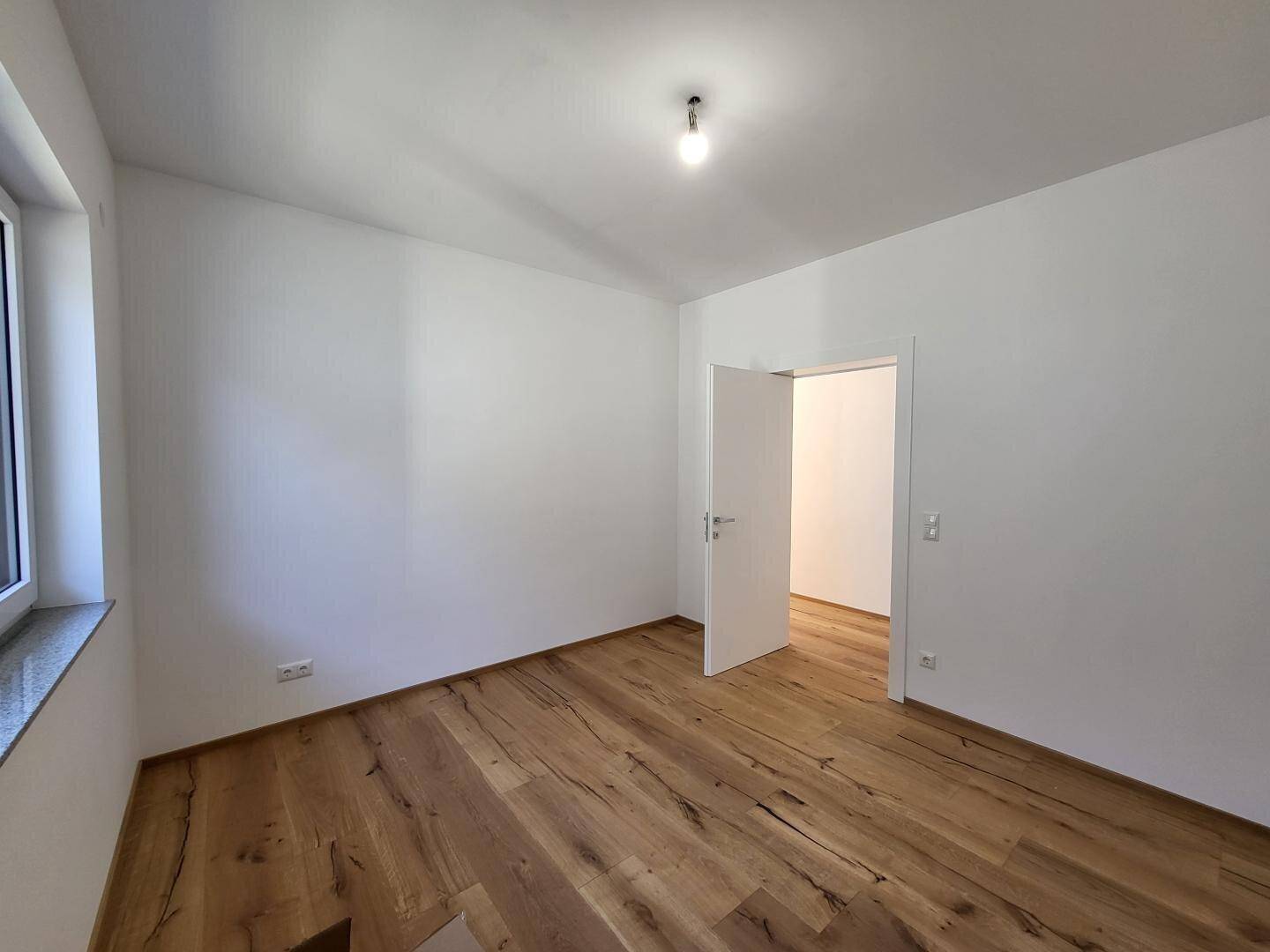 Leeres Schlafzimmer mit Holzboden und weiß gestrichenen Wänden, bereit zum Einrichten.
