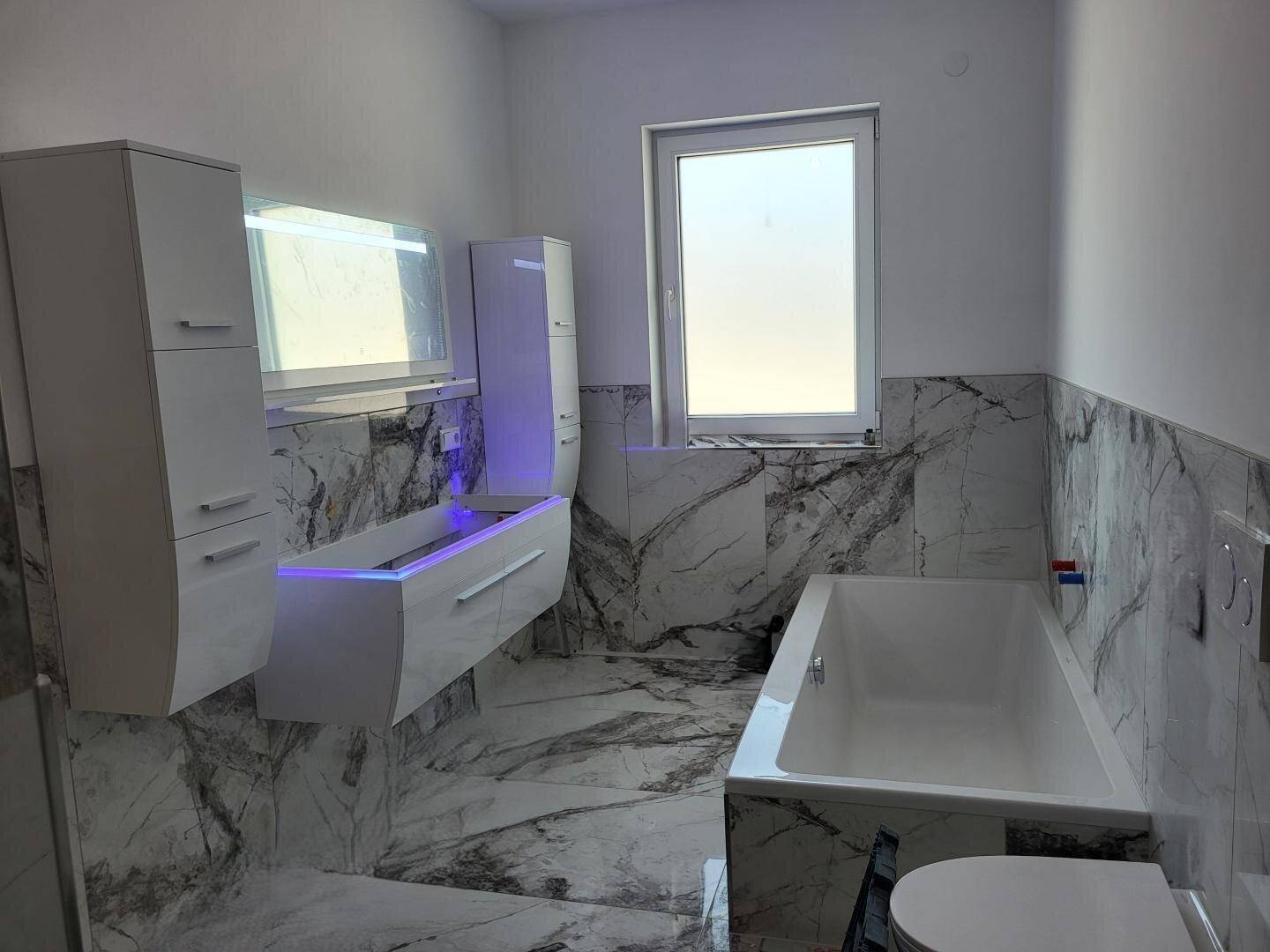 Geräumiges Badezimmer mit Badewanne, modernem Waschtisch und Fenster für Tageslicht.