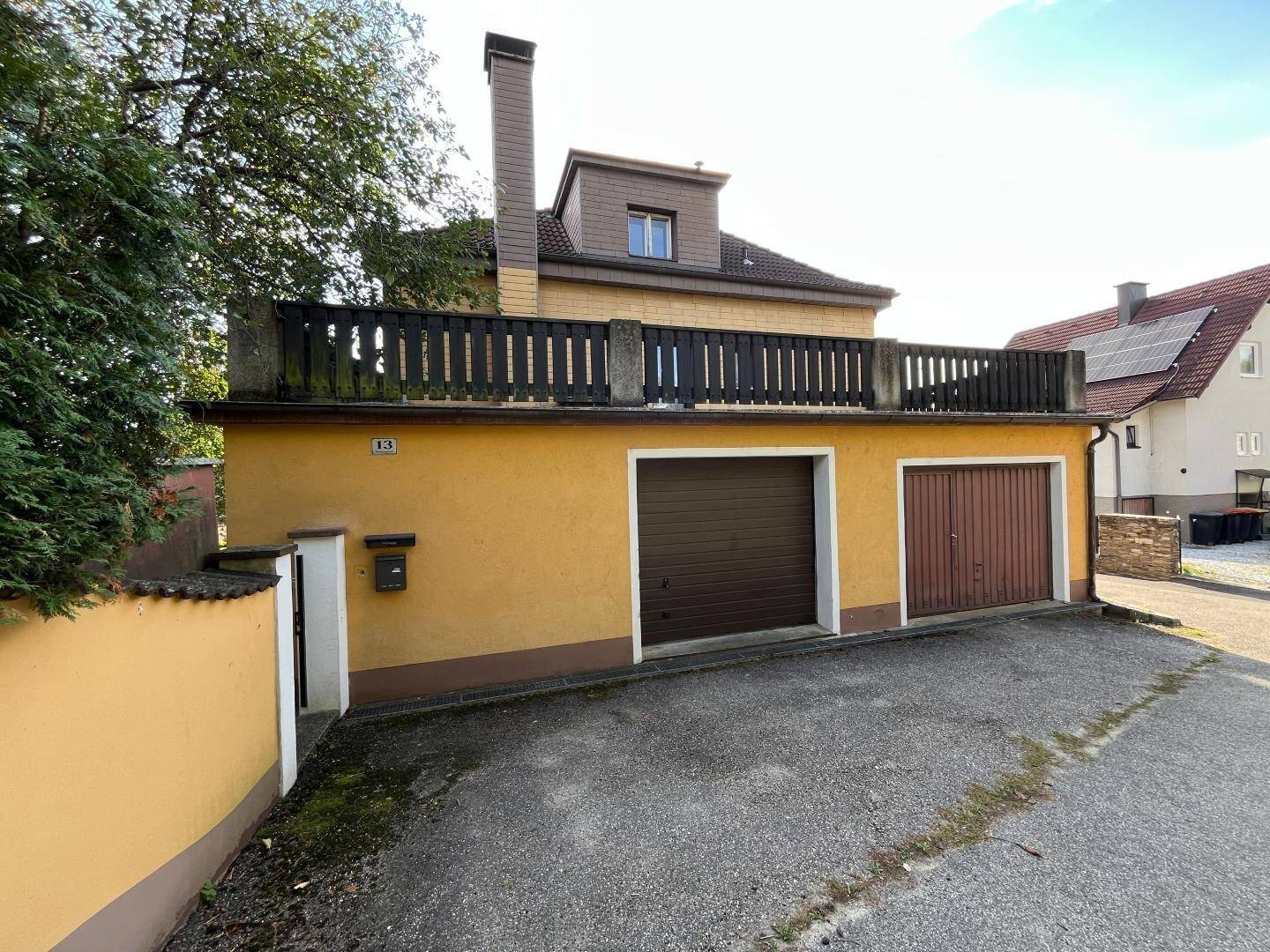 Garagenbereich des Hauses mit zwei Toren und der darüberliegenden Terrasse.
