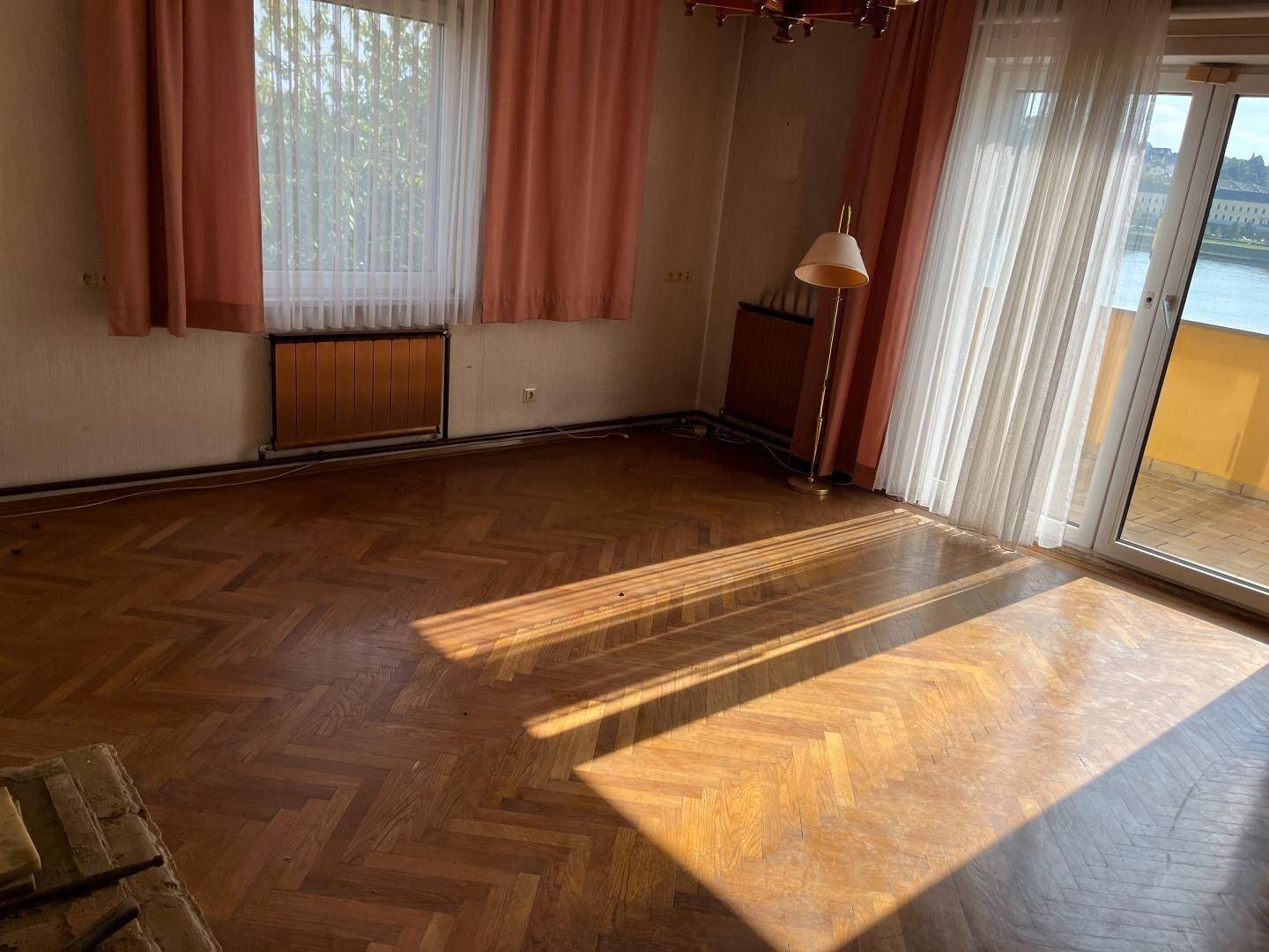 Helles Wohnzimmer mit sonnigem Fischgrätparkett und Blick nach draußen.