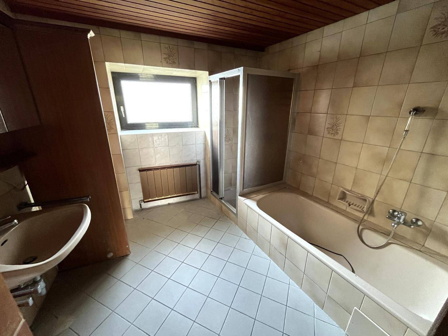 Badezimmer im 80er-Jahre-Stil mit Fliesen, Badewanne, Duschkabine und Einzelwaschbecken.