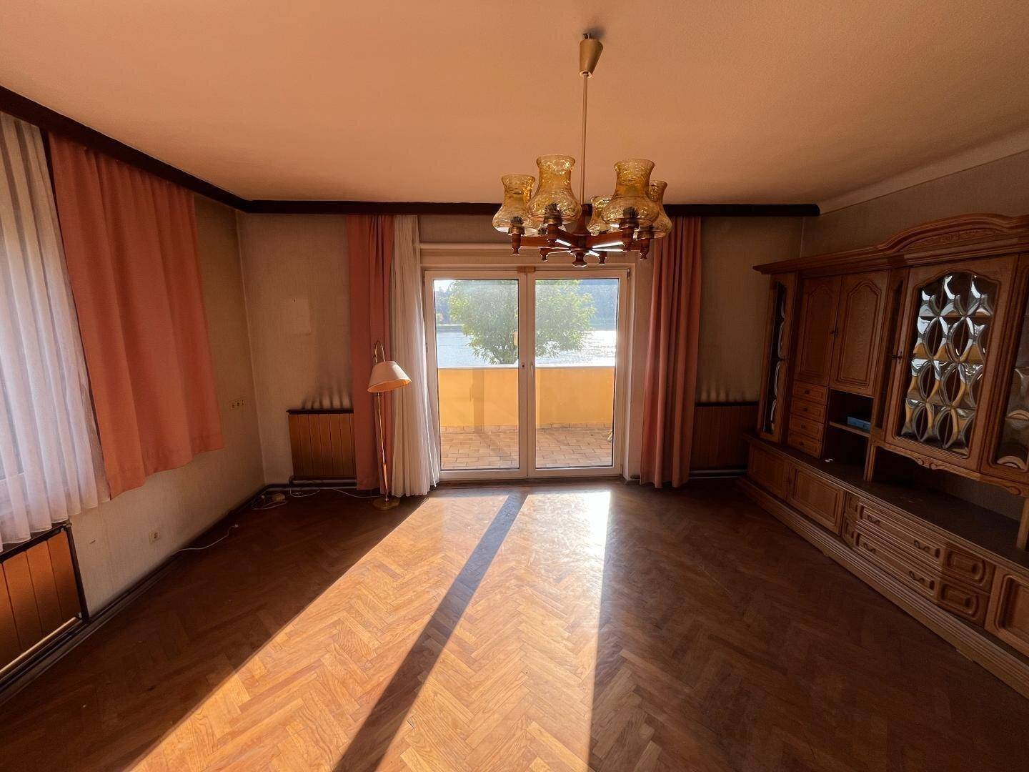 Geräumiges Wohnzimmer mit Fischgrätparkett und direktem Zugang zur Terrasse.