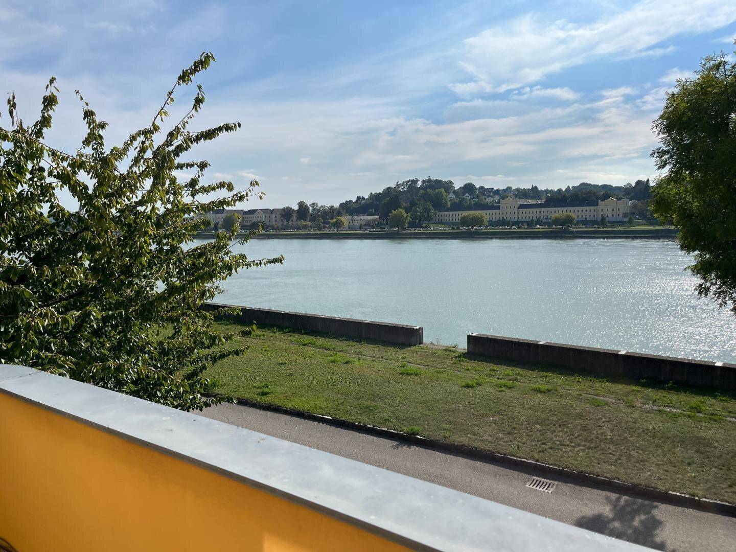 Panoramablick vom Balkon auf den breiten Fluss und die gegenüberliegende Stadtkulisse.
