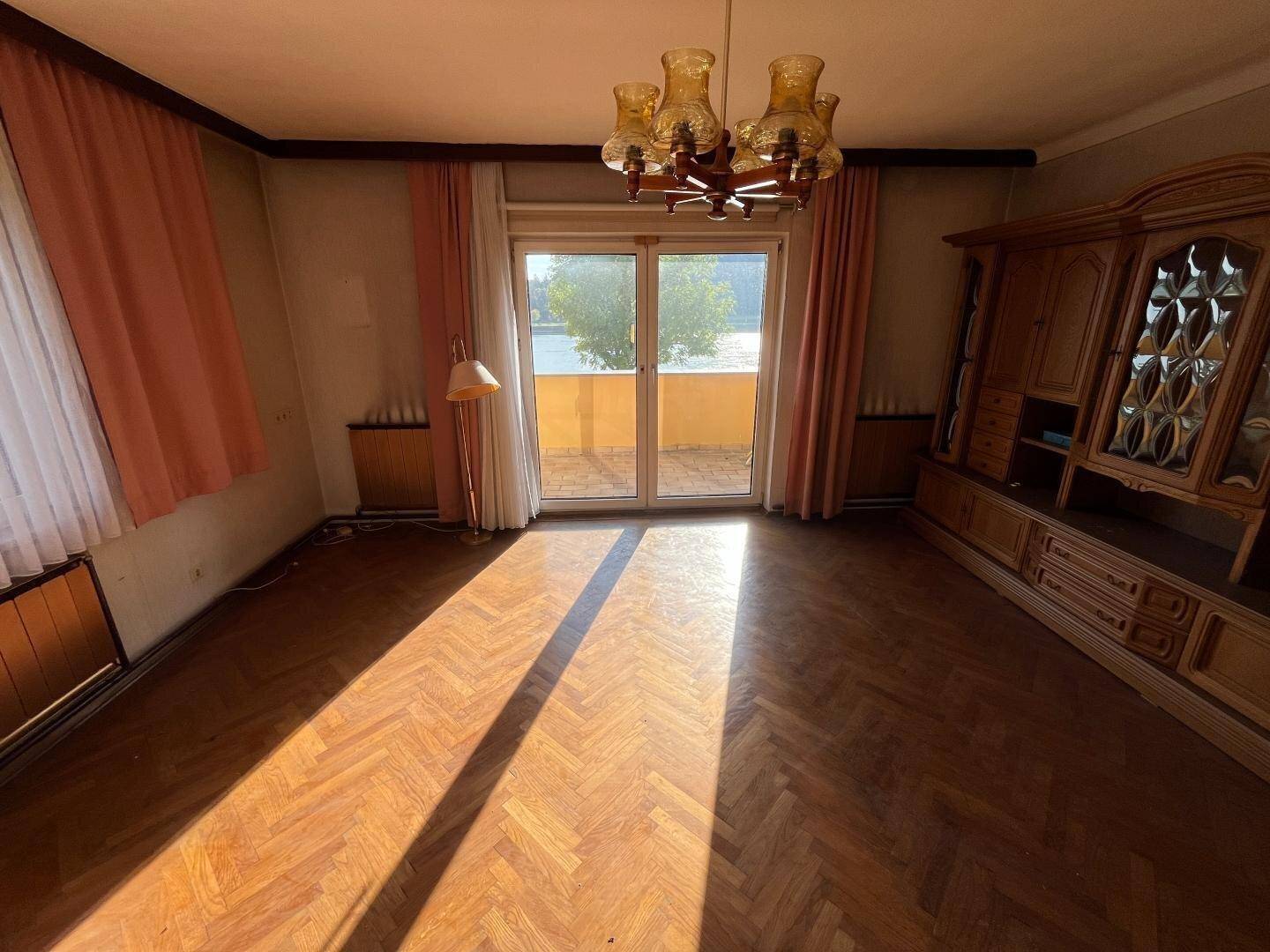 Helles Wohnzimmer mit Fischgrätparkett, Zugang zum Balkon und traditionellen Möbeln.