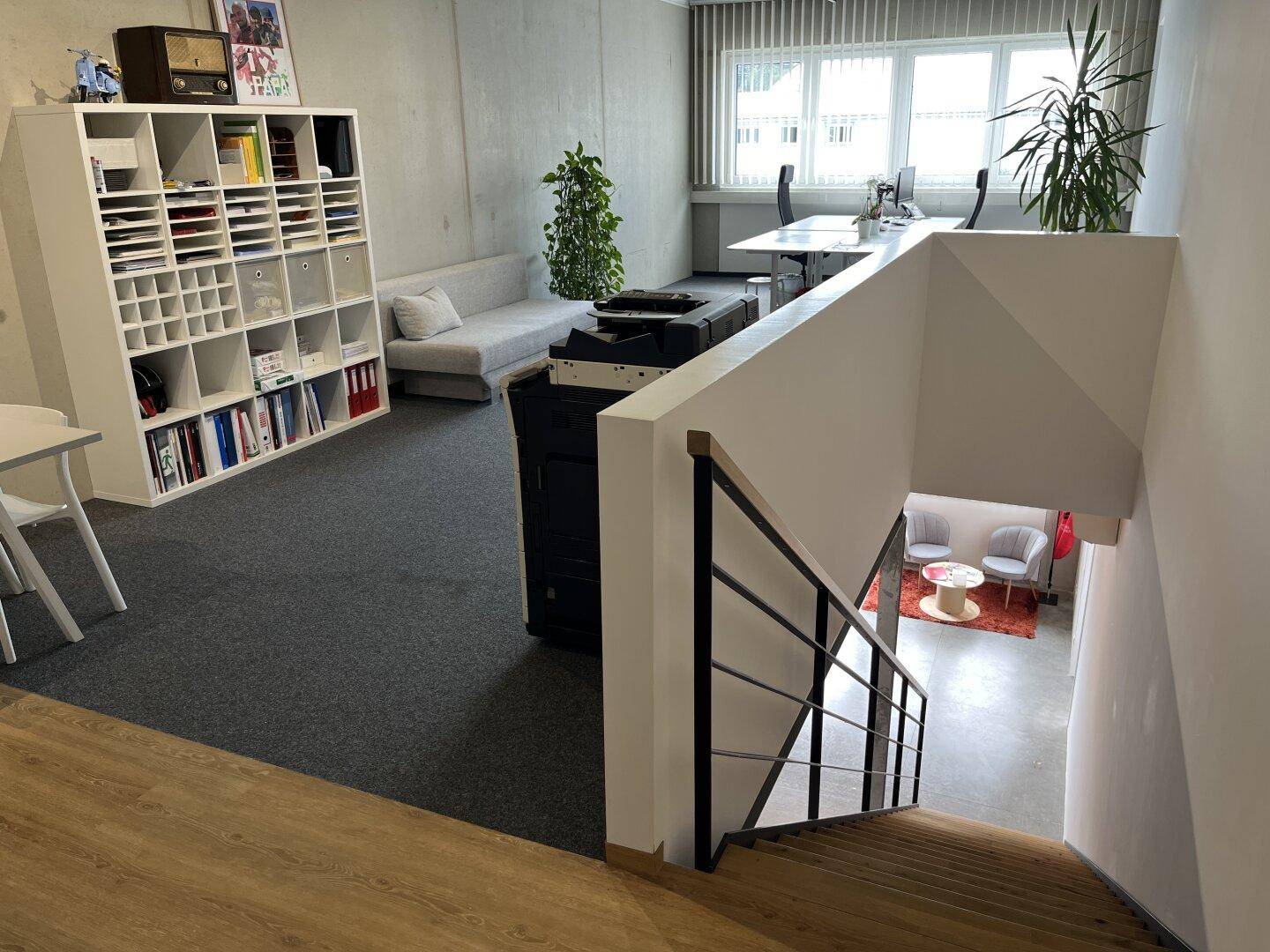 Helles Büro mit Teppichboden, großen Fenstern und Blick auf die Umgebung.