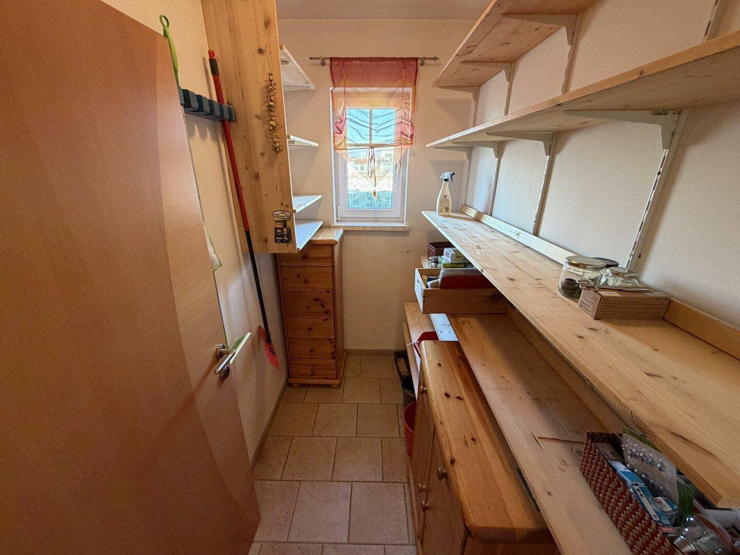 Praktische Speisekammer mit vielen Regalen und einem Fenster für gute Belüftung.