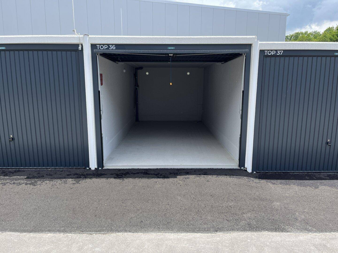 Offene, leere Garagenbox mit weiß gestrichenen Wänden und Betonboden, bereit zur Nutzung.
