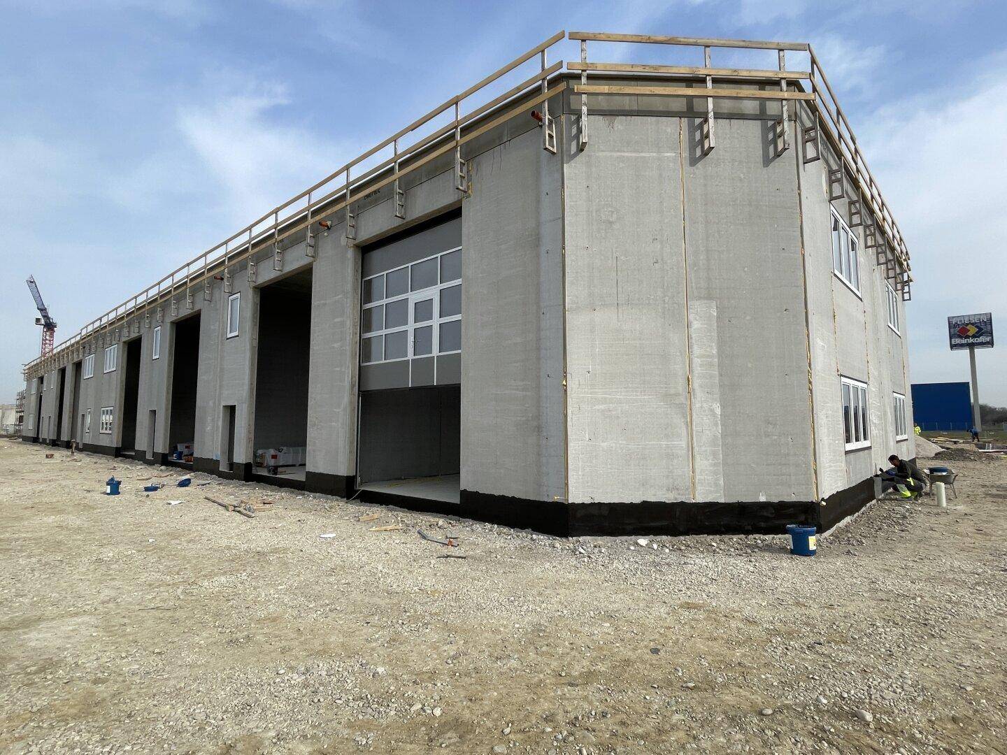 Gewerbegebäude in Bauphase mit großer Toröffnung und Betonwänden, bereit für den Innenausbau.