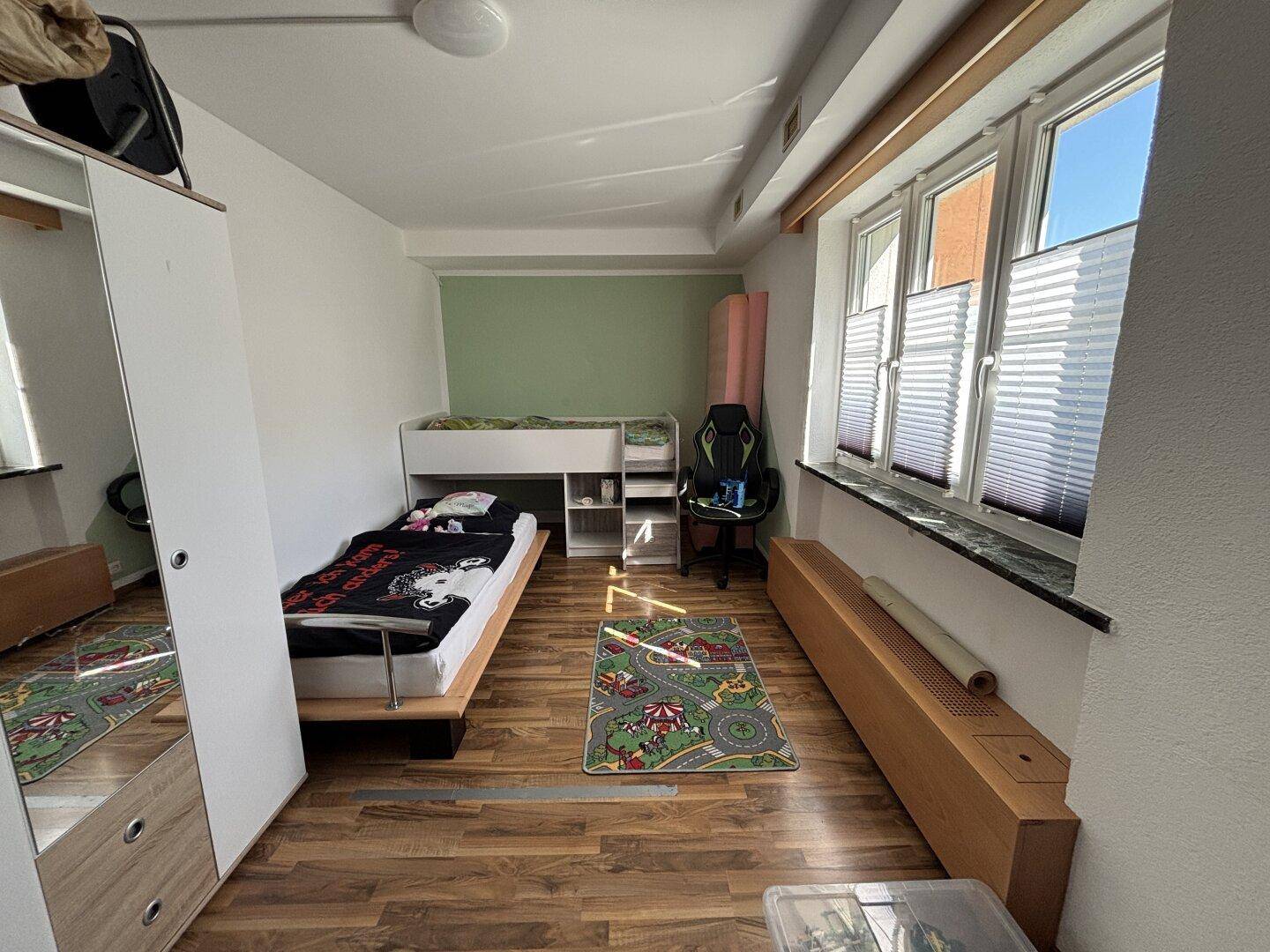 Kinderzimmer mit Hochbett, Holzfußboden und hellem Tageslicht.