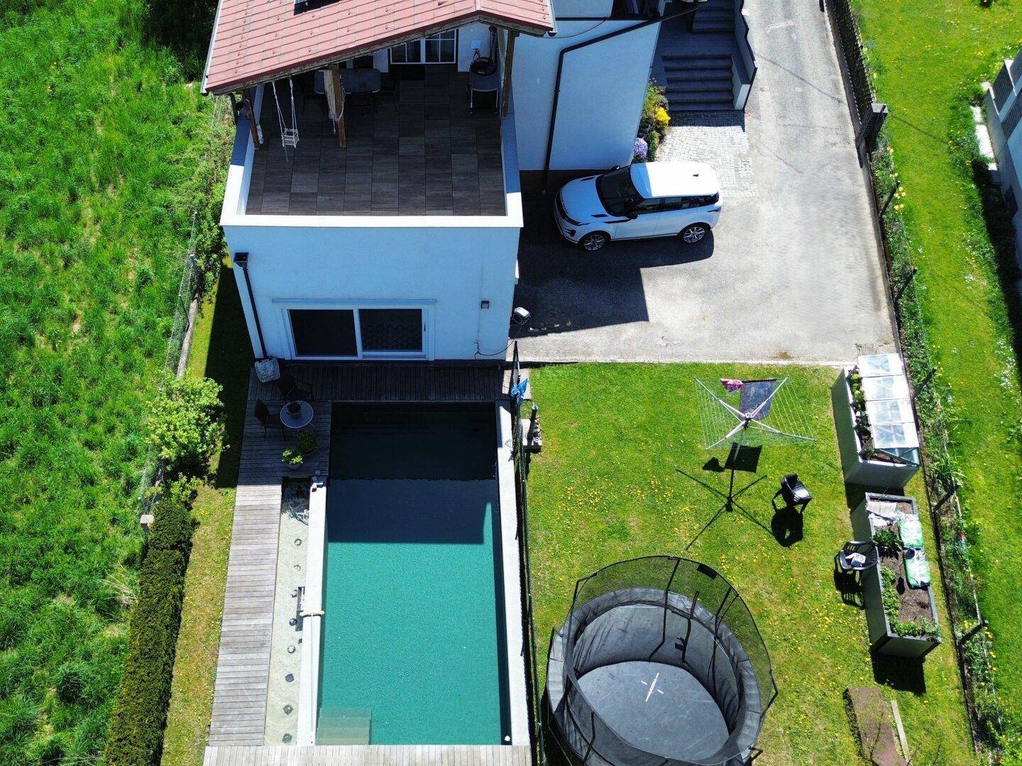 Draufsicht auf das Wohnhaus mit Swimmingpool, großem Garten und sonniger Terrasse.