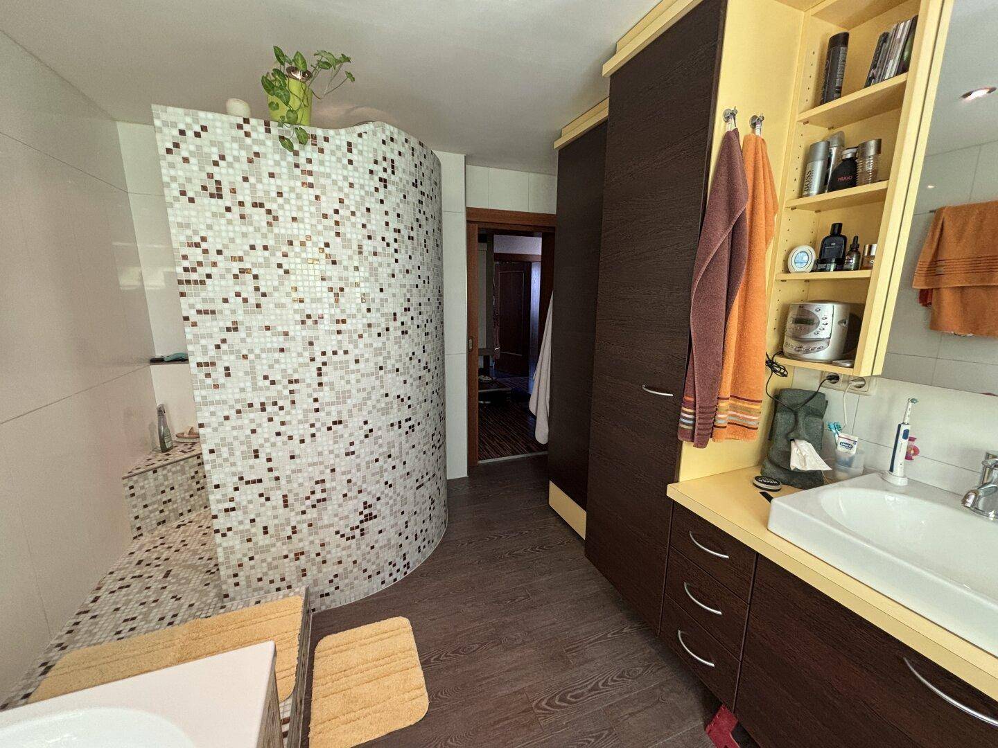 Badezimmer mit begehbarer Dusche, Einzelwaschbecken und modernen Fliesen.