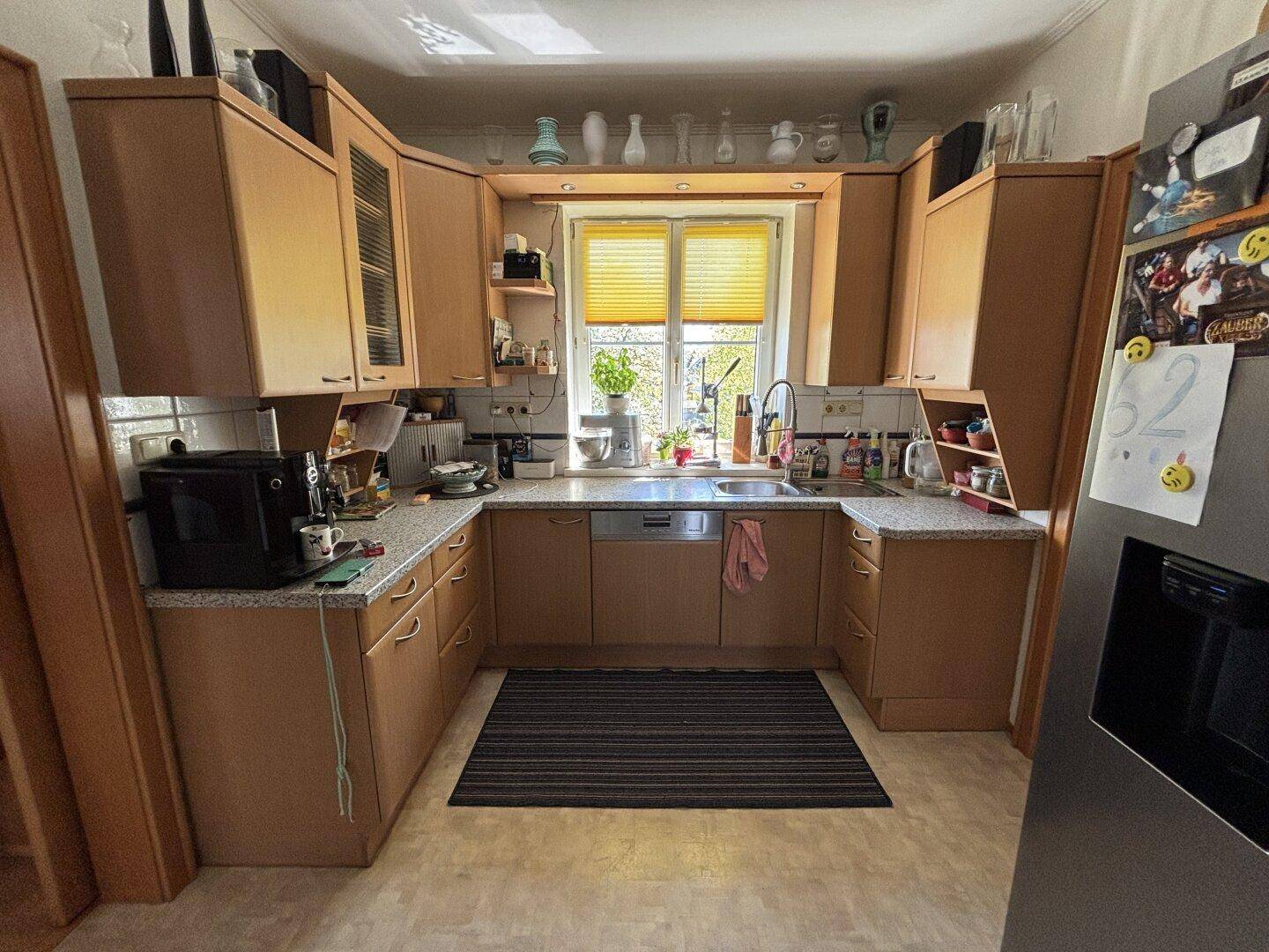 Küche mit U-förmiger Anordnung, Holzschränken und Fenster über der Spüle.