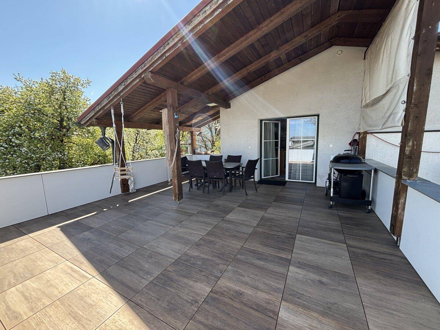 Große überdachte Terrasse mit Fliesenboden, Essbereich und Grill für gesellige Stunden.