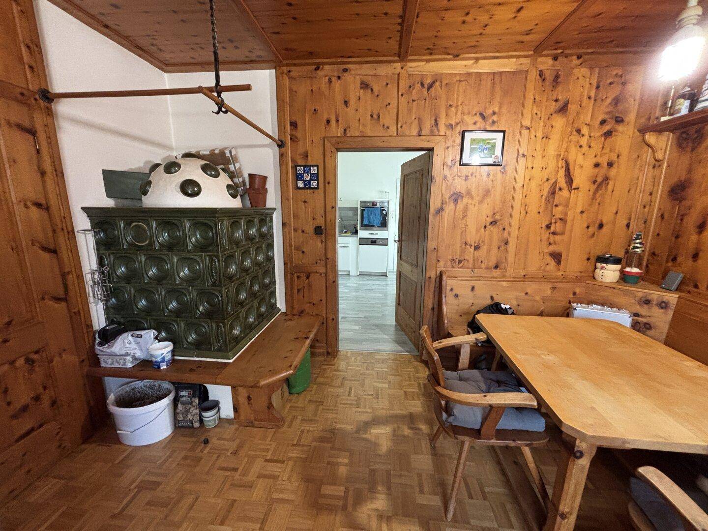 Gemütlicher Essbereich mit Holztäfelung, traditionellem Kachelofen und Holzboden.