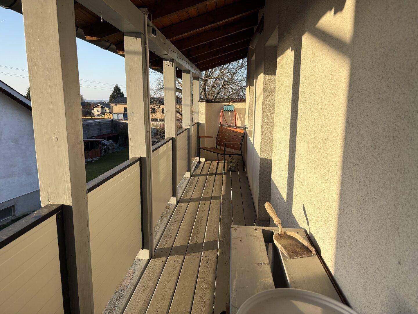 Schmaler Balkon mit Holzboden und Geländer, ideal für einen ruhigen Morgenkaffee.