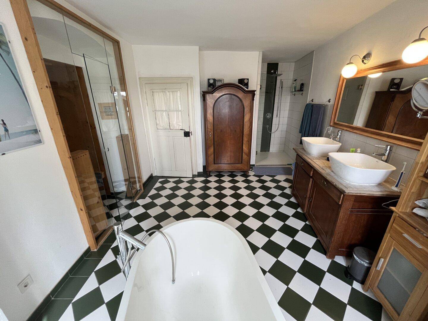Badezimmer mit freistehender Badewanne, Dusche und integrierter Sauna für Wellnessmomente.