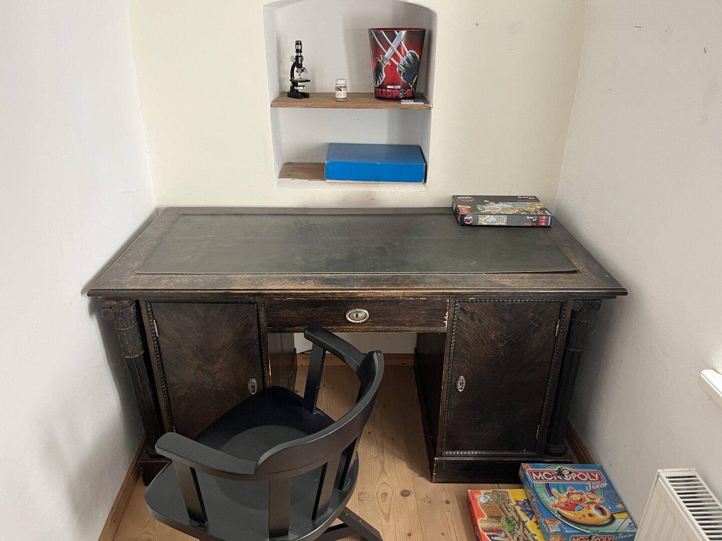 Kleiner Raum mit einem antiken Holzschreibtisch und einem Stuhl, ideal als Arbeitsplatz.