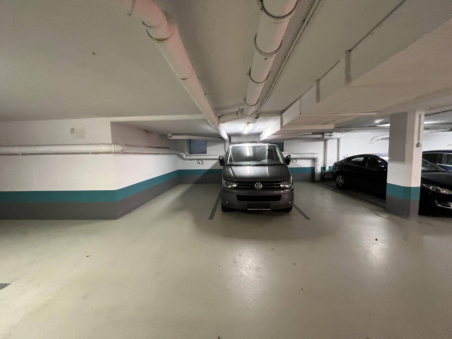 Geräumiger Stellplatz in der Tiefgarage mit einem geparkten Van und guter Beleuchtung.